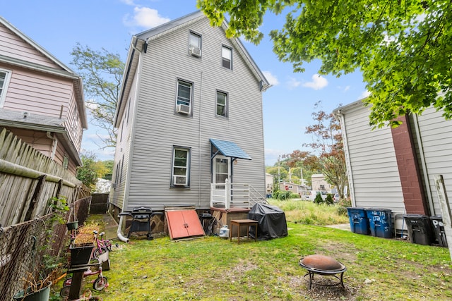 rear view of property with a lawn and cooling unit