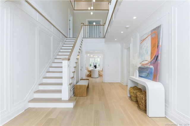 foyer entrance featuring light hardwood / wood-style flooring, crown molding, and a high ceiling