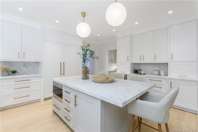 kitchen with pendant lighting, stainless steel microwave, tasteful backsplash, and white cabinetry