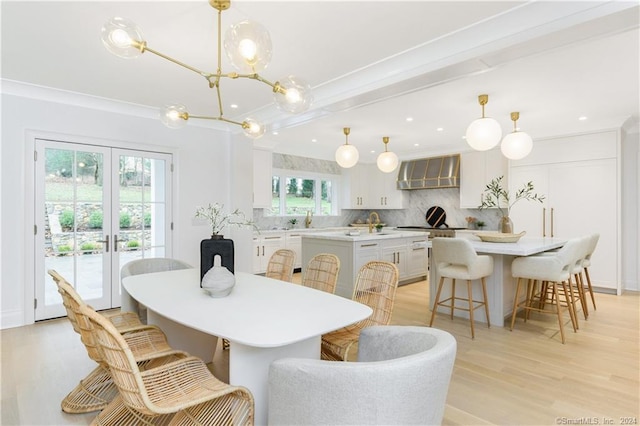 dining area with french doors, a notable chandelier, light hardwood / wood-style flooring, and crown molding