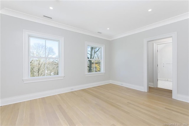 unfurnished room featuring light wood-type flooring, ornamental molding, and a wealth of natural light