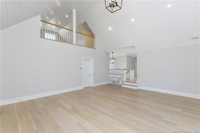 unfurnished living room featuring light wood-type flooring, wood ceiling, an inviting chandelier, and high vaulted ceiling