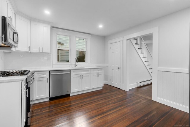 kitchen with appliances with stainless steel finishes, white cabinets, a baseboard radiator, dark hardwood / wood-style floors, and sink