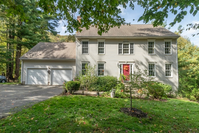 colonial inspired home with a garage and a front lawn