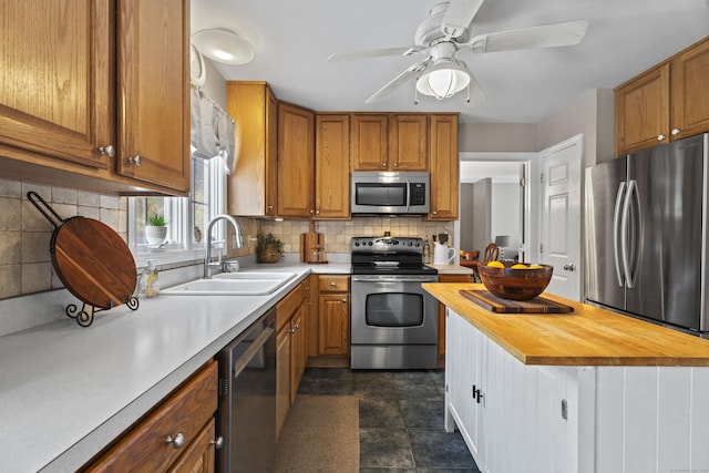 kitchen with butcher block countertops, sink, ceiling fan, appliances with stainless steel finishes, and backsplash