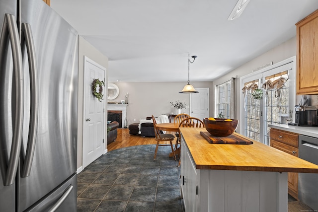 kitchen with a kitchen island, butcher block countertops, decorative light fixtures, stainless steel appliances, and light brown cabinets