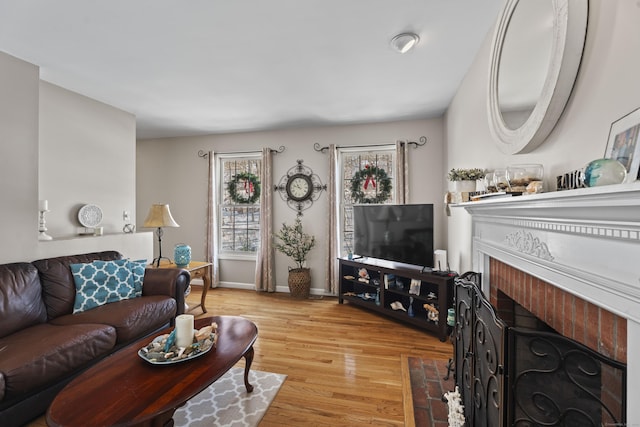 living room featuring a brick fireplace and light wood-type flooring