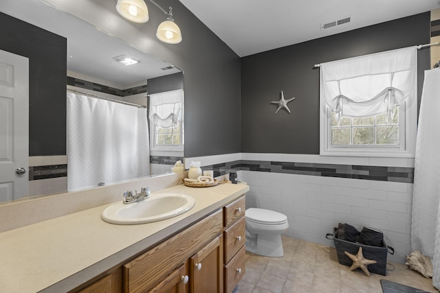 bathroom featuring vanity, tile walls, tile patterned floors, and toilet