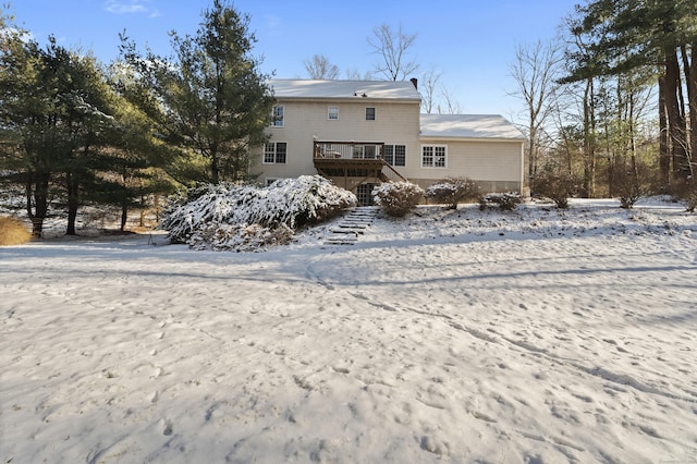 snow covered back of property with a wooden deck