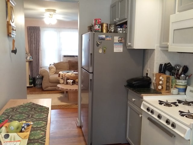 kitchen with gray cabinets, wood-type flooring, decorative backsplash, white appliances, and ceiling fan