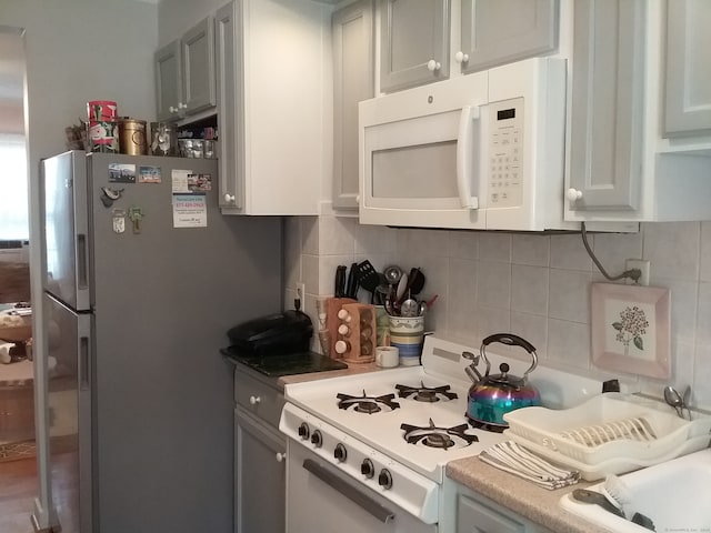 kitchen featuring decorative backsplash and white appliances