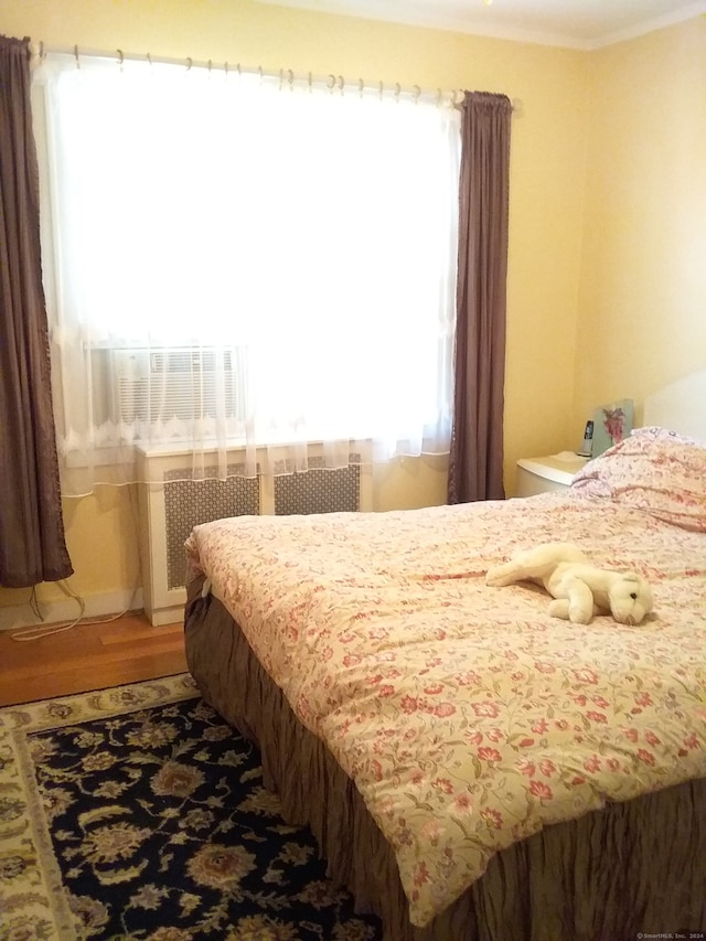 bedroom featuring wood-type flooring and radiator heating unit