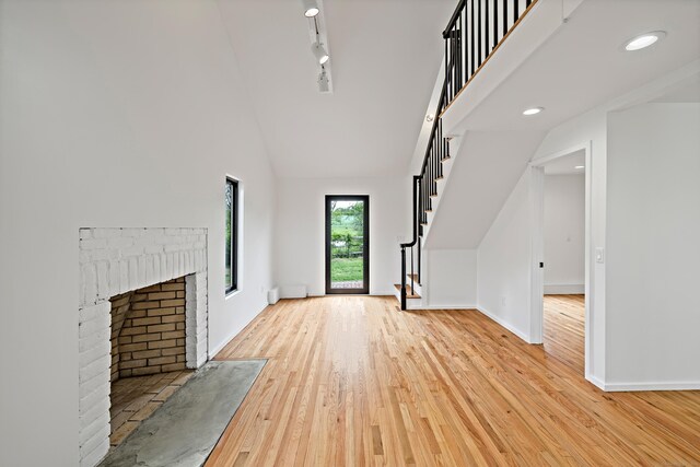 429 Chestnut Land Rd, New Milford, CT 06776 - unfurnished living room with light wood-style flooring, a towering ceiling, baseboards, and stairs