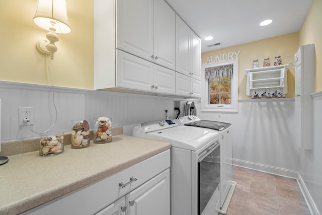 laundry room with washer and clothes dryer, cabinets, and light tile patterned floors