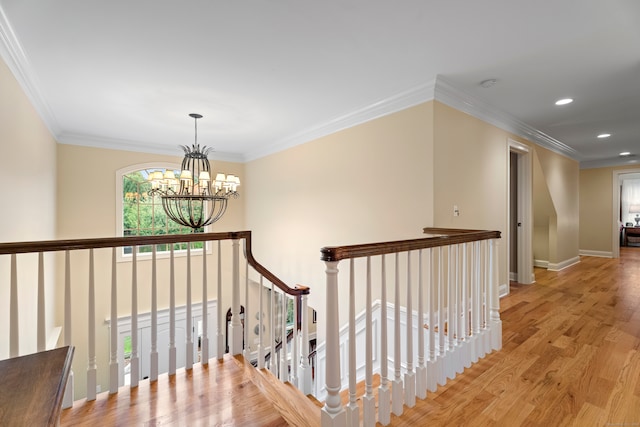 corridor with light wood-type flooring, crown molding, plenty of natural light, and a notable chandelier