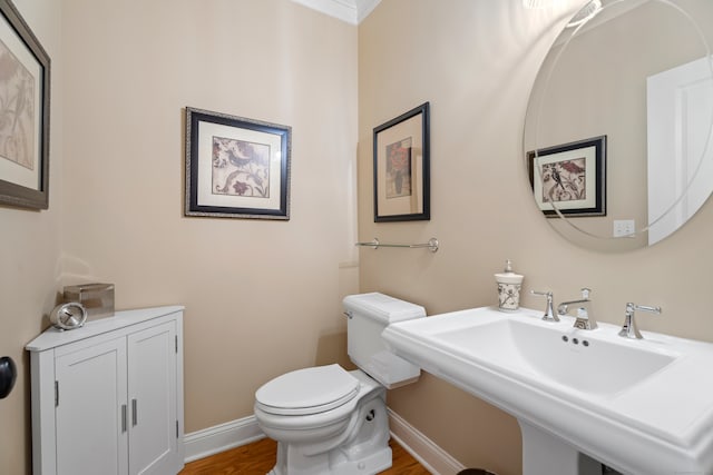 bathroom with hardwood / wood-style floors, ornamental molding, toilet, and sink