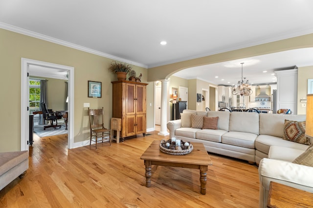 living room featuring ornamental molding, light wood-type flooring, decorative columns, and a notable chandelier