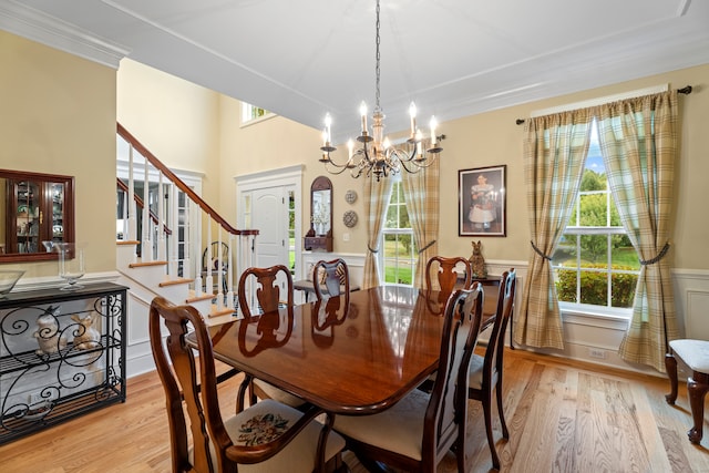 dining room with light wood-type flooring, ornamental molding, and an inviting chandelier