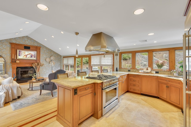 kitchen with stainless steel range, island range hood, light stone counters, and a healthy amount of sunlight