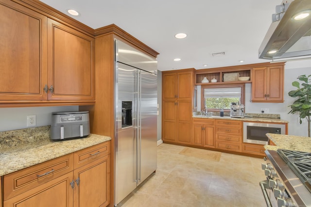 kitchen featuring light stone countertops, sink, built in appliances, light tile patterned floors, and exhaust hood