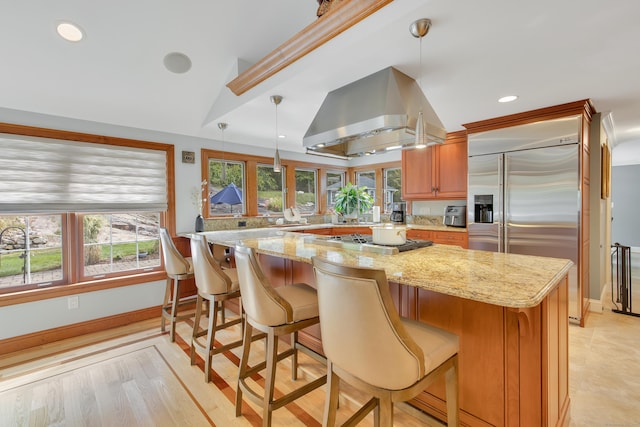 kitchen with plenty of natural light, light stone counters, and island exhaust hood