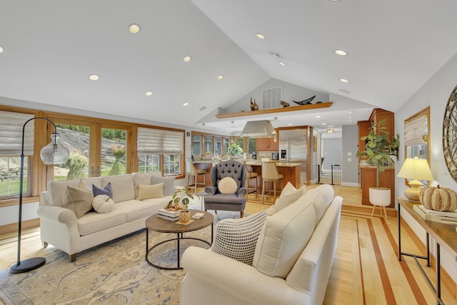 living room with light hardwood / wood-style floors, high vaulted ceiling, and french doors