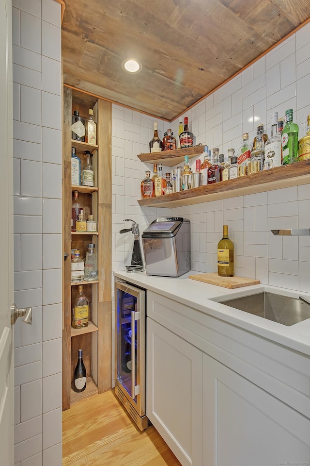 interior space with white cabinets, wine cooler, light hardwood / wood-style flooring, and wood ceiling