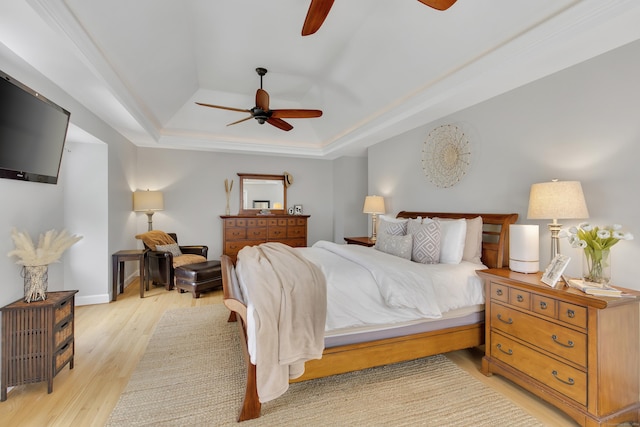 bedroom with a tray ceiling, ceiling fan, and light hardwood / wood-style floors