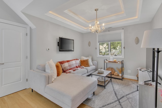 living room with a raised ceiling, light wood-type flooring, and a chandelier