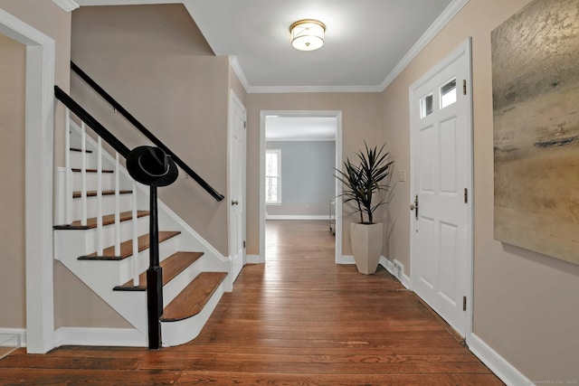 entryway featuring wood-type flooring, stairs, baseboards, and crown molding