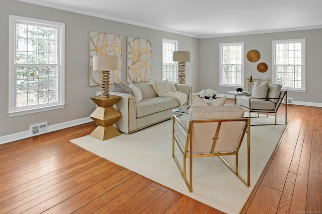 living room with visible vents, crown molding, baseboards, and hardwood / wood-style flooring