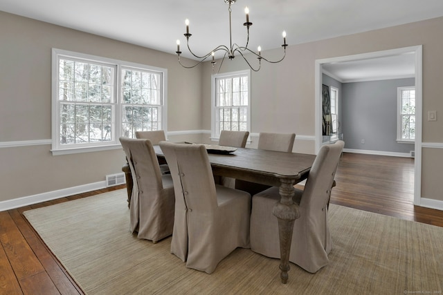 dining area with light wood-type flooring, an inviting chandelier, visible vents, and baseboards