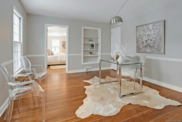 office space featuring wood-type flooring, visible vents, and baseboards