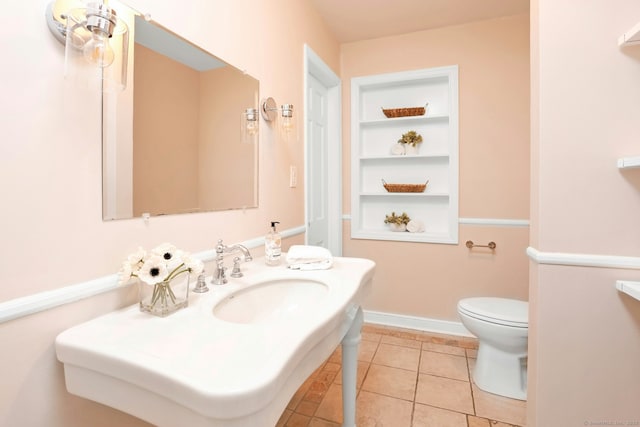 bathroom featuring built in shelves, tile patterned flooring, toilet, a sink, and baseboards