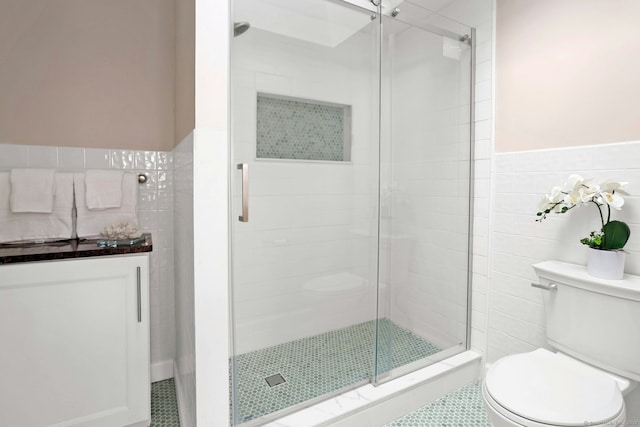 full bathroom featuring toilet, a wainscoted wall, a shower stall, and tile walls