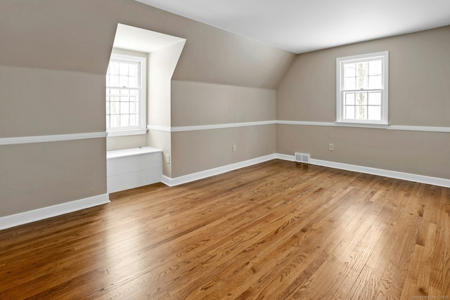 additional living space featuring a healthy amount of sunlight, visible vents, baseboards, and hardwood / wood-style floors