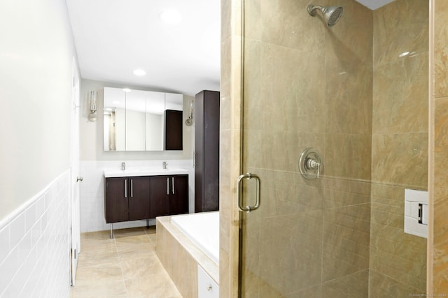 full bathroom with double vanity, a stall shower, tile walls, tile patterned floors, and a sink