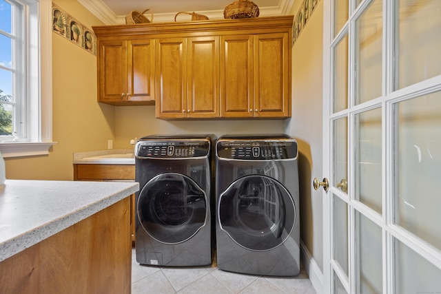 washroom with cabinets, crown molding, light tile patterned floors, and washing machine and dryer