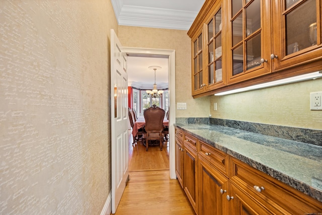 interior space with ornamental molding, an inviting chandelier, and light hardwood / wood-style floors