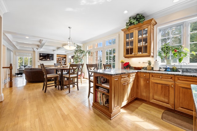 kitchen featuring light wood-type flooring, kitchen peninsula, ornamental molding, and dark stone counters