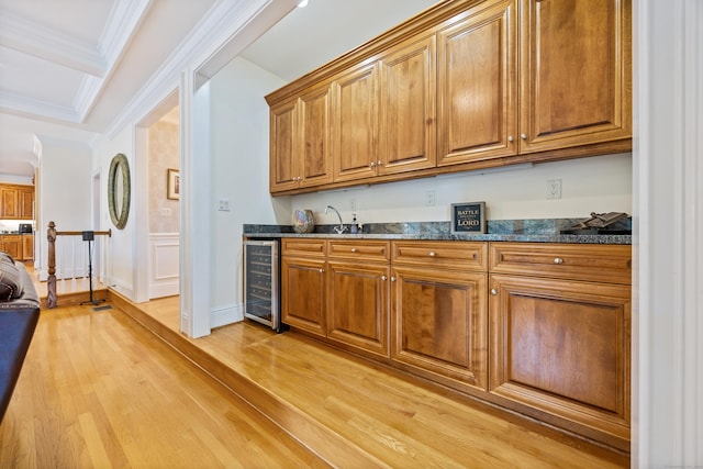 kitchen featuring dark stone counters, light hardwood / wood-style floors, crown molding, and wine cooler