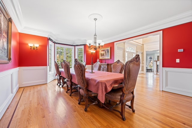 dining room with light hardwood / wood-style floors, crown molding, and a notable chandelier