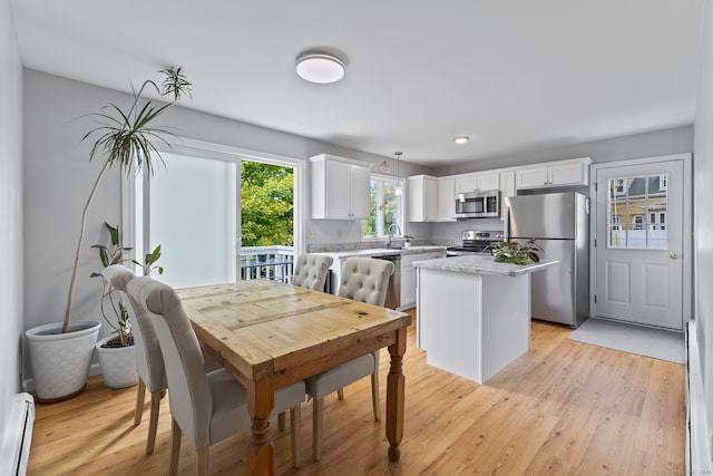 dining area featuring a baseboard radiator, light hardwood / wood-style flooring, and sink