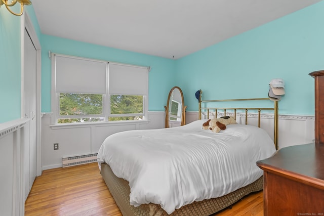 bedroom with light hardwood / wood-style floors and baseboard heating