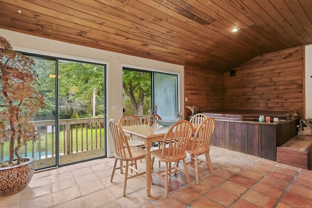 dining space featuring lofted ceiling, wood walls, a water view, and wooden ceiling