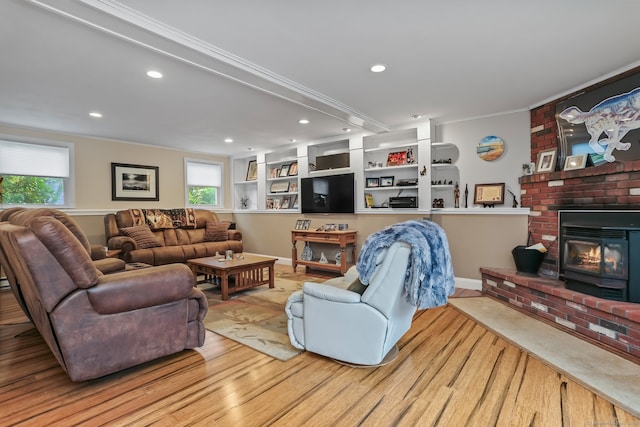 living room with crown molding, light hardwood / wood-style flooring, and a brick fireplace