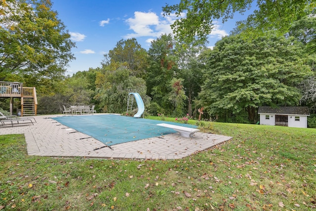 view of swimming pool featuring a diving board, a water slide, a patio area, a deck, and a yard