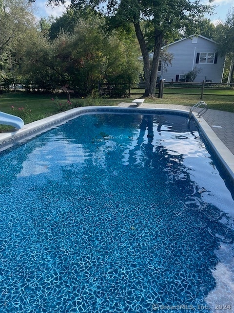 view of pool featuring a lawn, a diving board, and a water slide