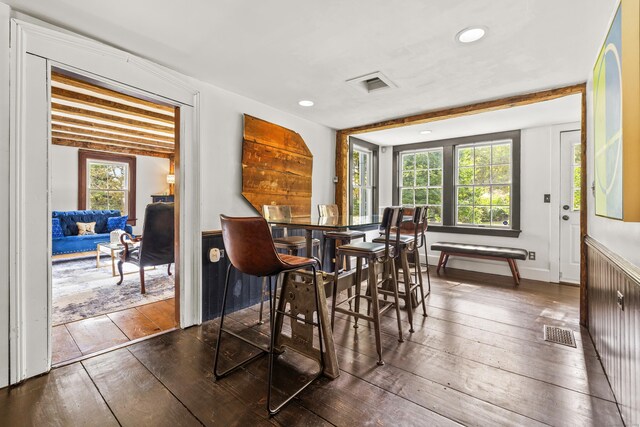 dining room featuring beamed ceiling, plenty of natural light, and wood-type flooring