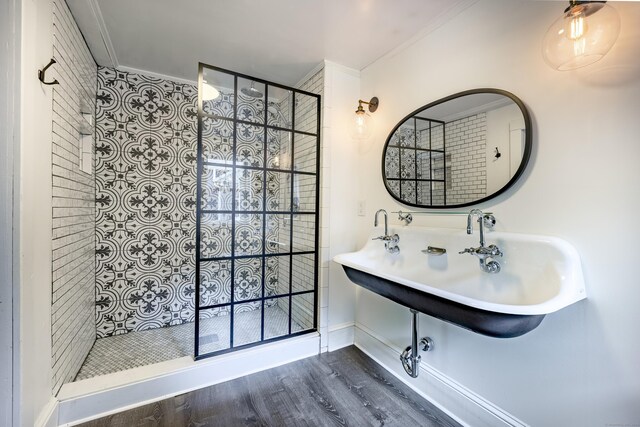 bathroom featuring wood-type flooring, crown molding, sink, and tiled shower